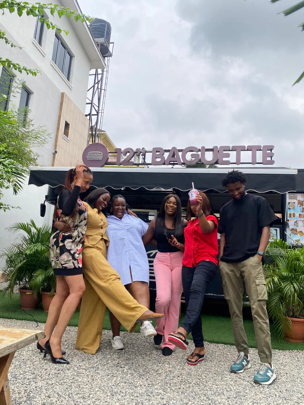 Six people posing playfully in front of a food truck