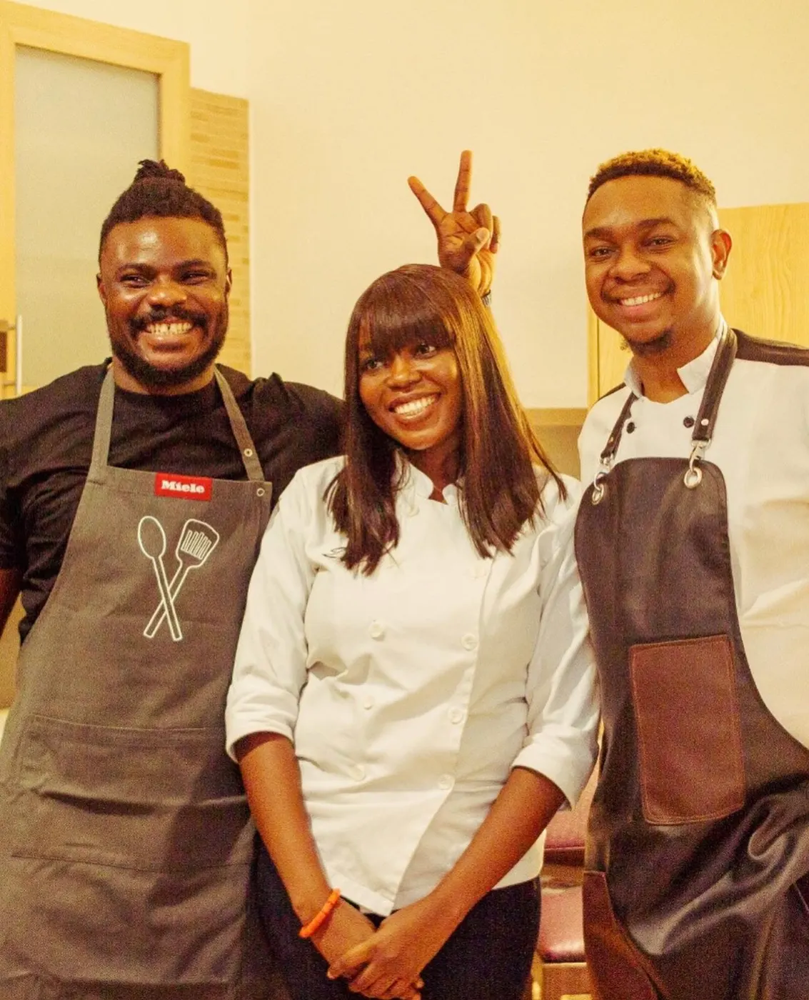 Two chefs and a colleague in chef whites posing together in aprons