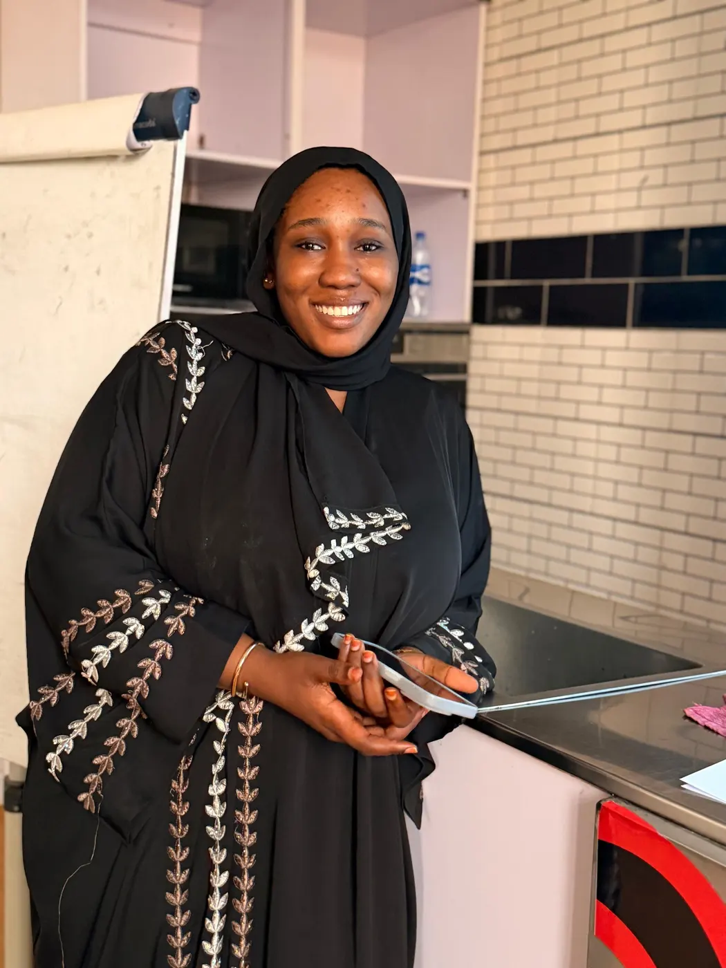 A student smiling in a training kitchen while holding a tray