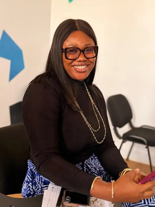 A woman in glasses smiling at a desk