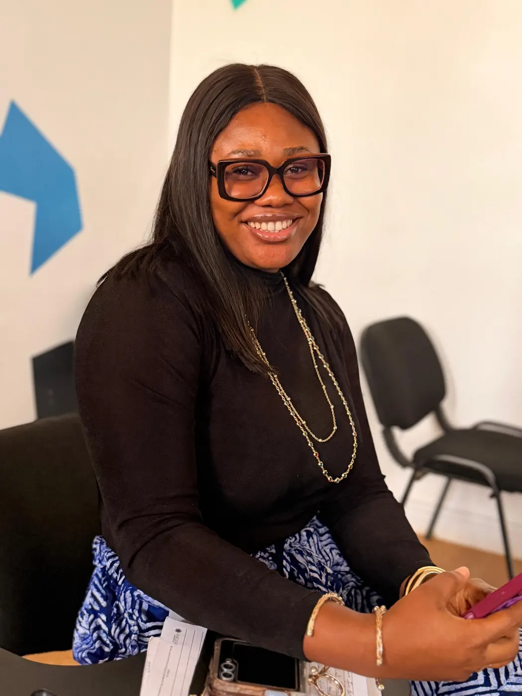 A woman in glasses smiling at a desk