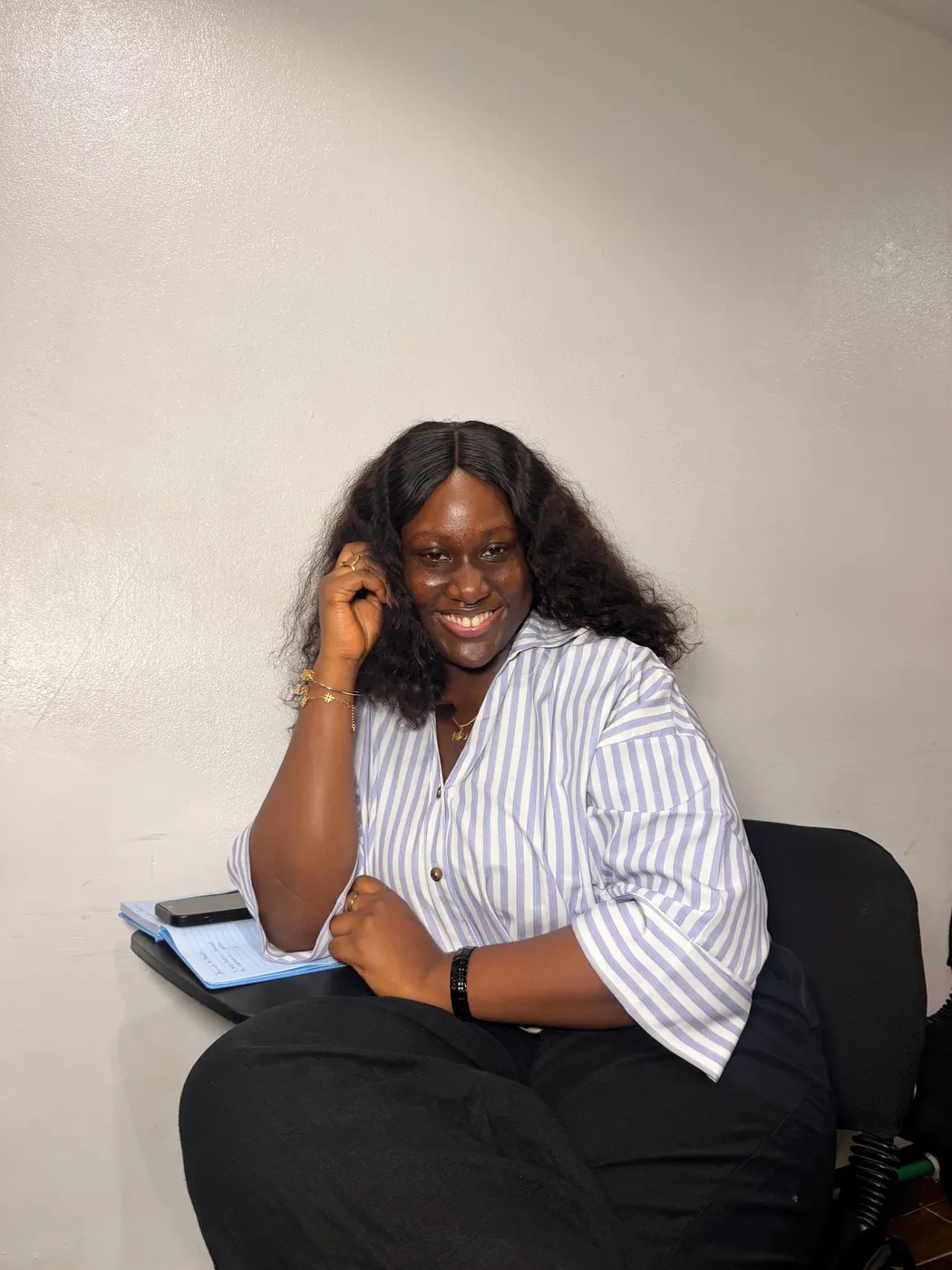A student seated with a notebook, smiling