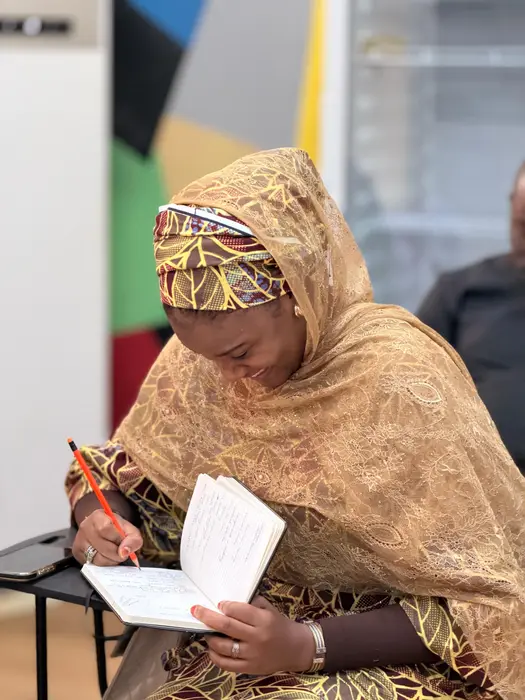 A student in gold lace writing notes in a notebook during a session