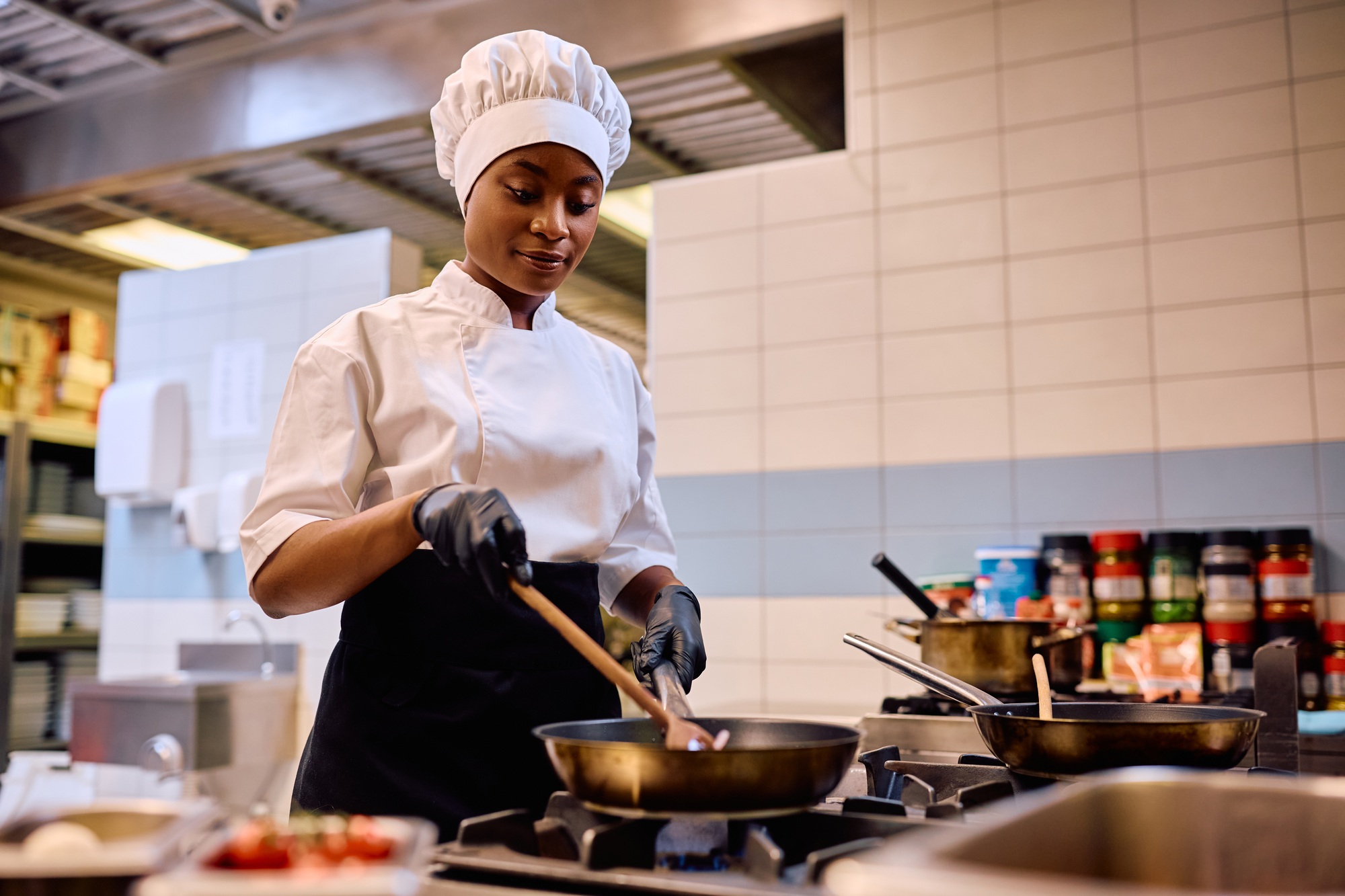 Black female chef cooking while working in the kitchen in a restaurant.